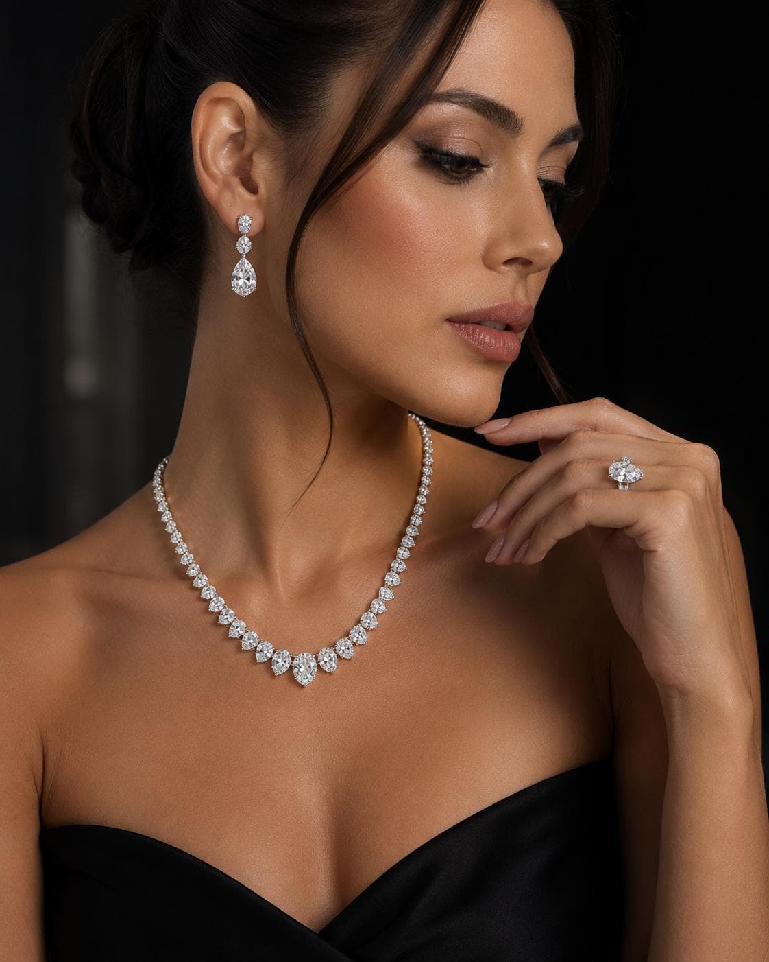 A woman wearing a graduated pear-cut diamond necklace, matching drop earrings and a diamond ring
